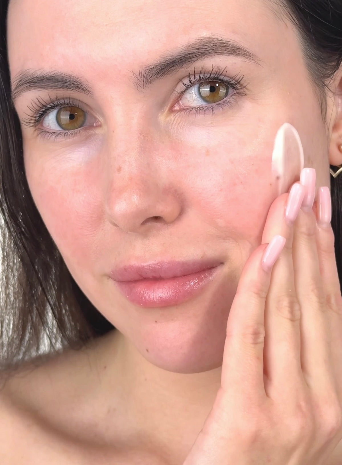 Woman applying moisturiser to her cheek